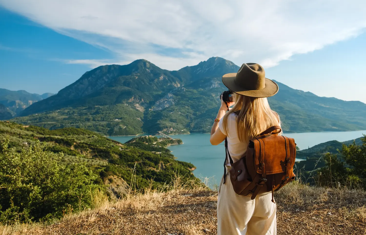 Fotografin mit großem Rucksack fotografiert Berge und blauen See. Reise- und Hobbykonzept